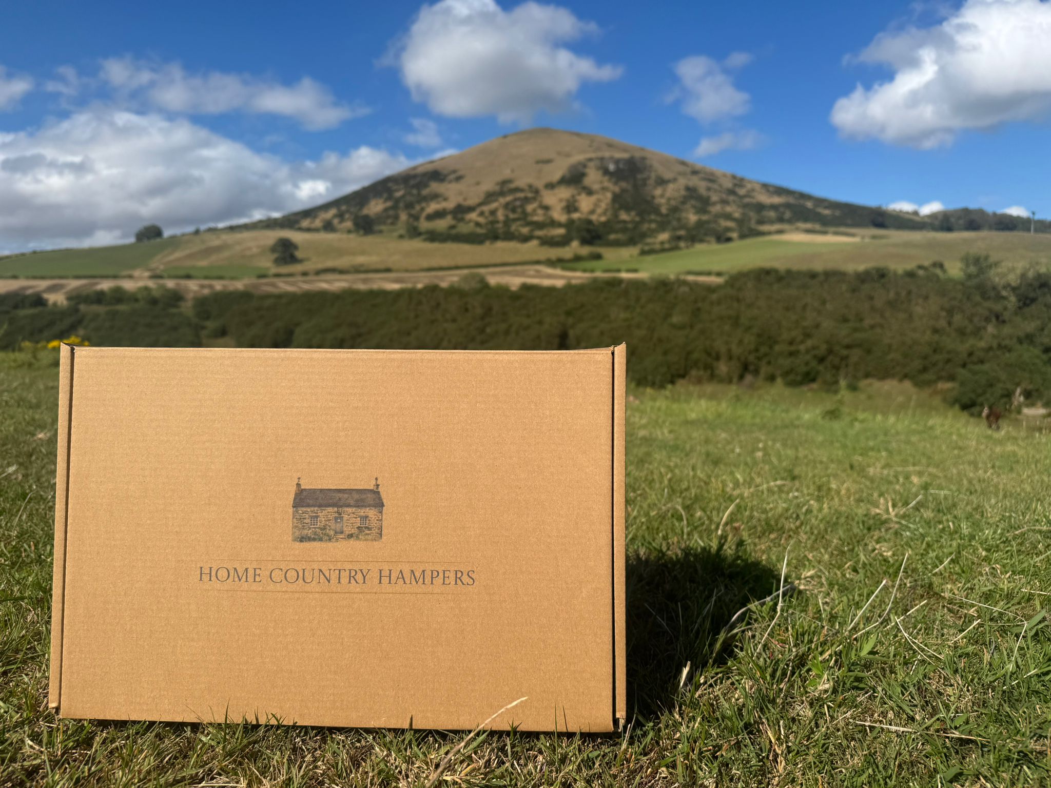 A home country hampers box sat on the grass in the countryside of Fife